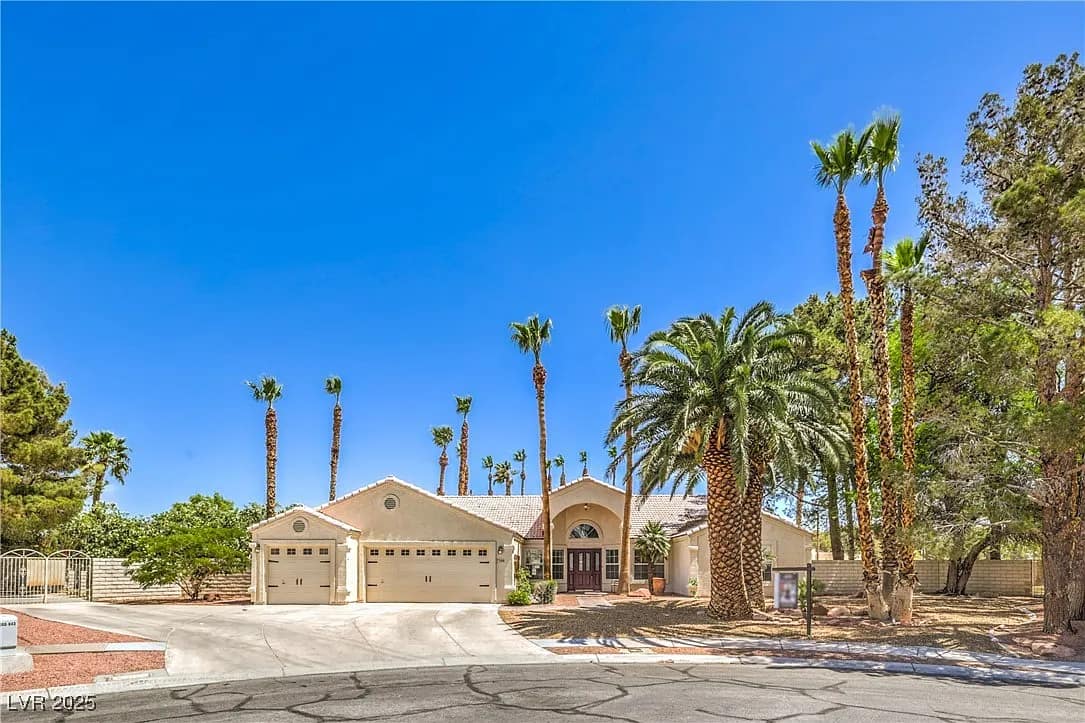 Single-story house with a three-car garage, surrounded by tall palm trees and desert landscaping, set against a clear blue sky—perfect for those looking to sell my home as is or a Better Home Buyer seeking effortless curb appeal.