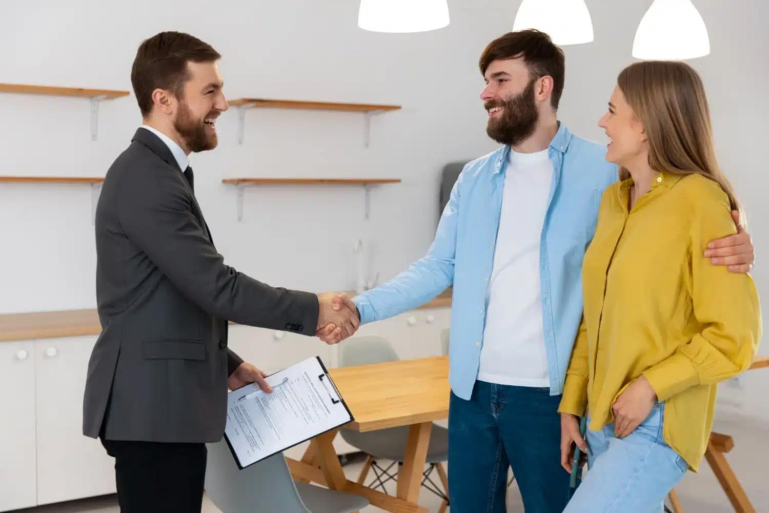 A man in a suit shakes hands with a casually dressed man, likely a cash buyer, while a woman stands beside them, smiling. The scene takes place in a bright, modern office—perfect for those looking to sell your house fast.